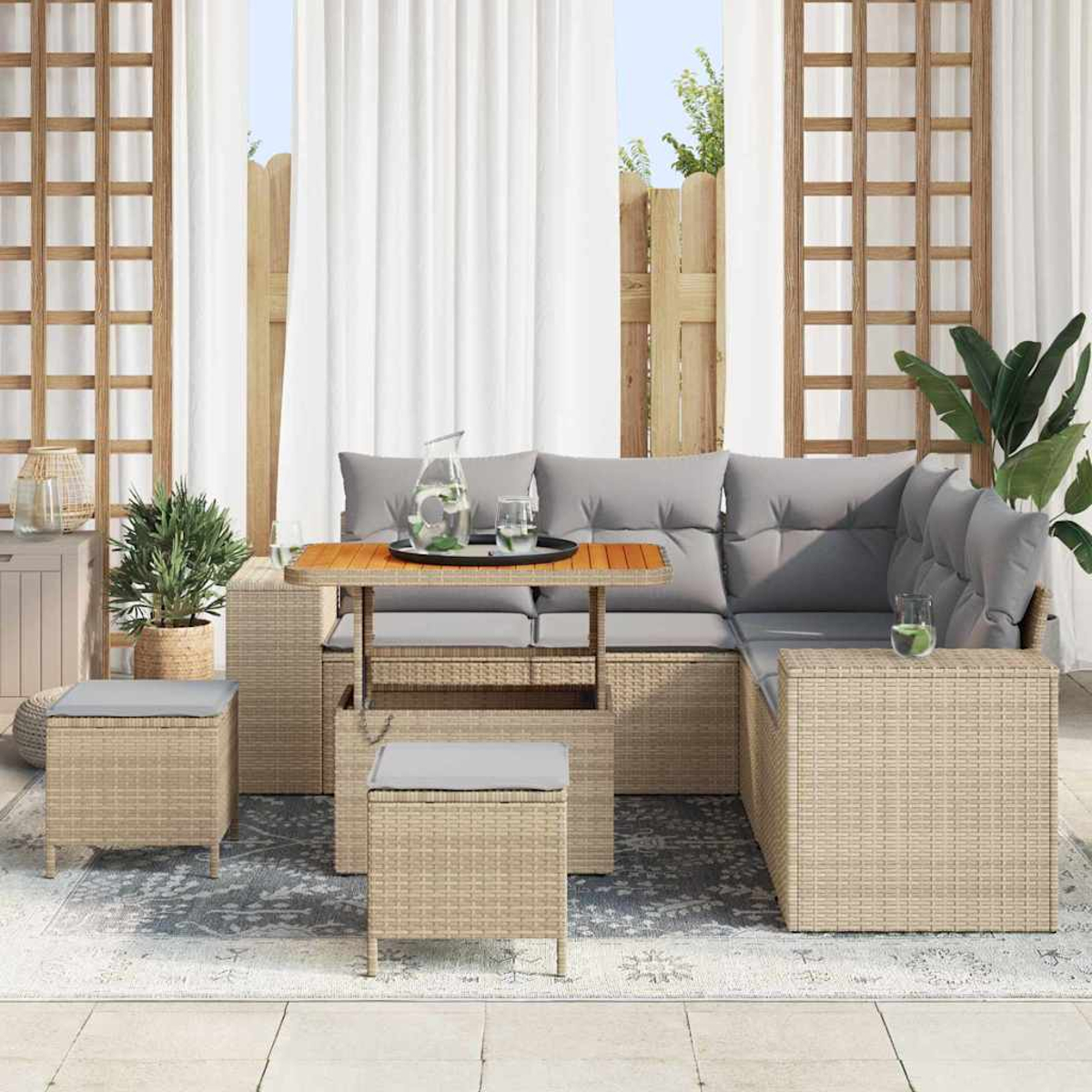 Outdoor-Sitzarrangement mit Tisch, Kissen und Hockern. Auf dem Tisch stehen ein Glaskrug und Gläser.