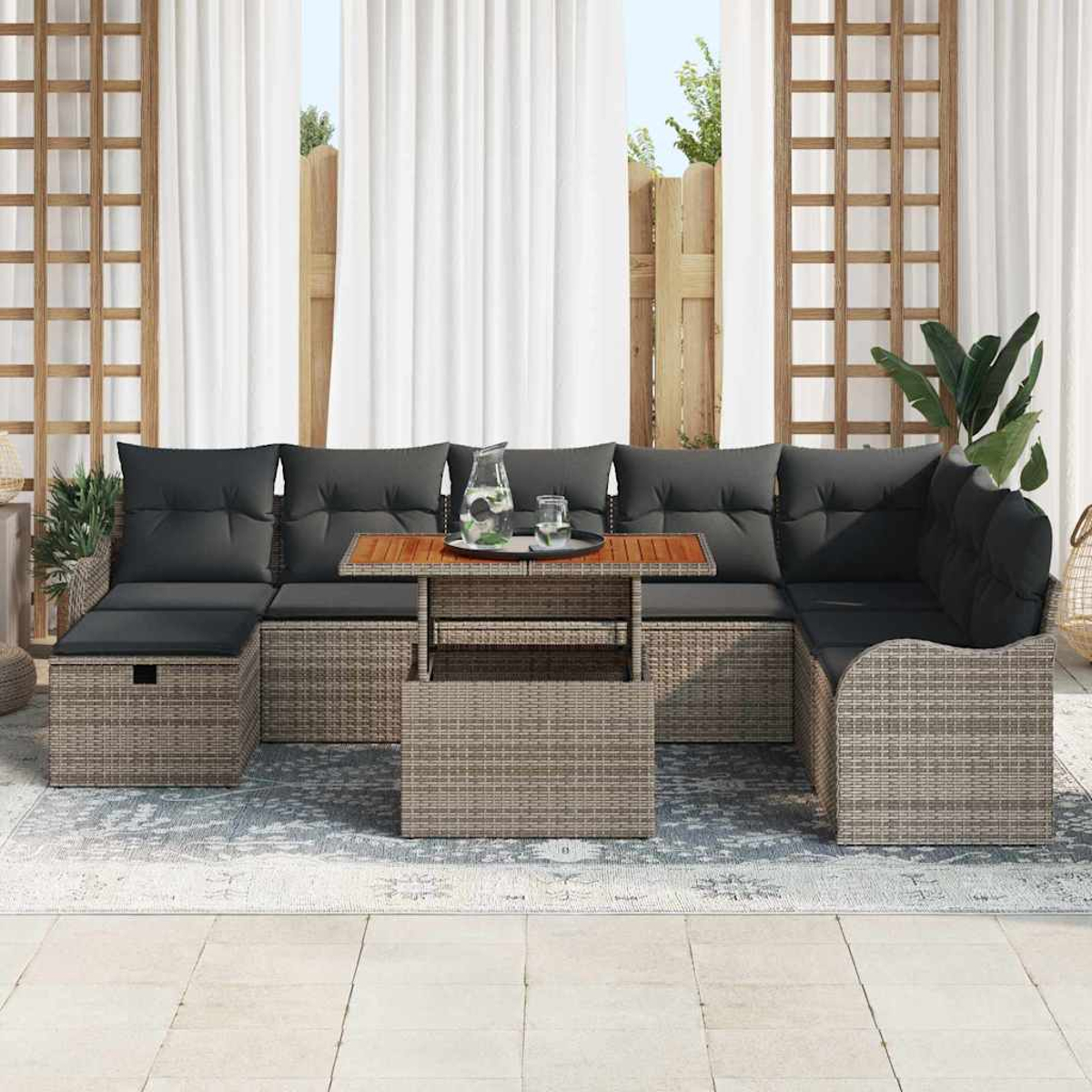 Ein Ecksofa für draußen mit grauen Kissen und einem Holztisch. Weiße Vorhänge und ein Zaun im Hintergrund.