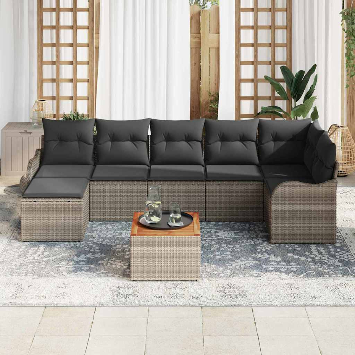 Outdoor-Ecksofa mit grauen Kissen, einem kleinen Tisch mit Getränken und einem gemusterten Teppich auf einer Terrasse.