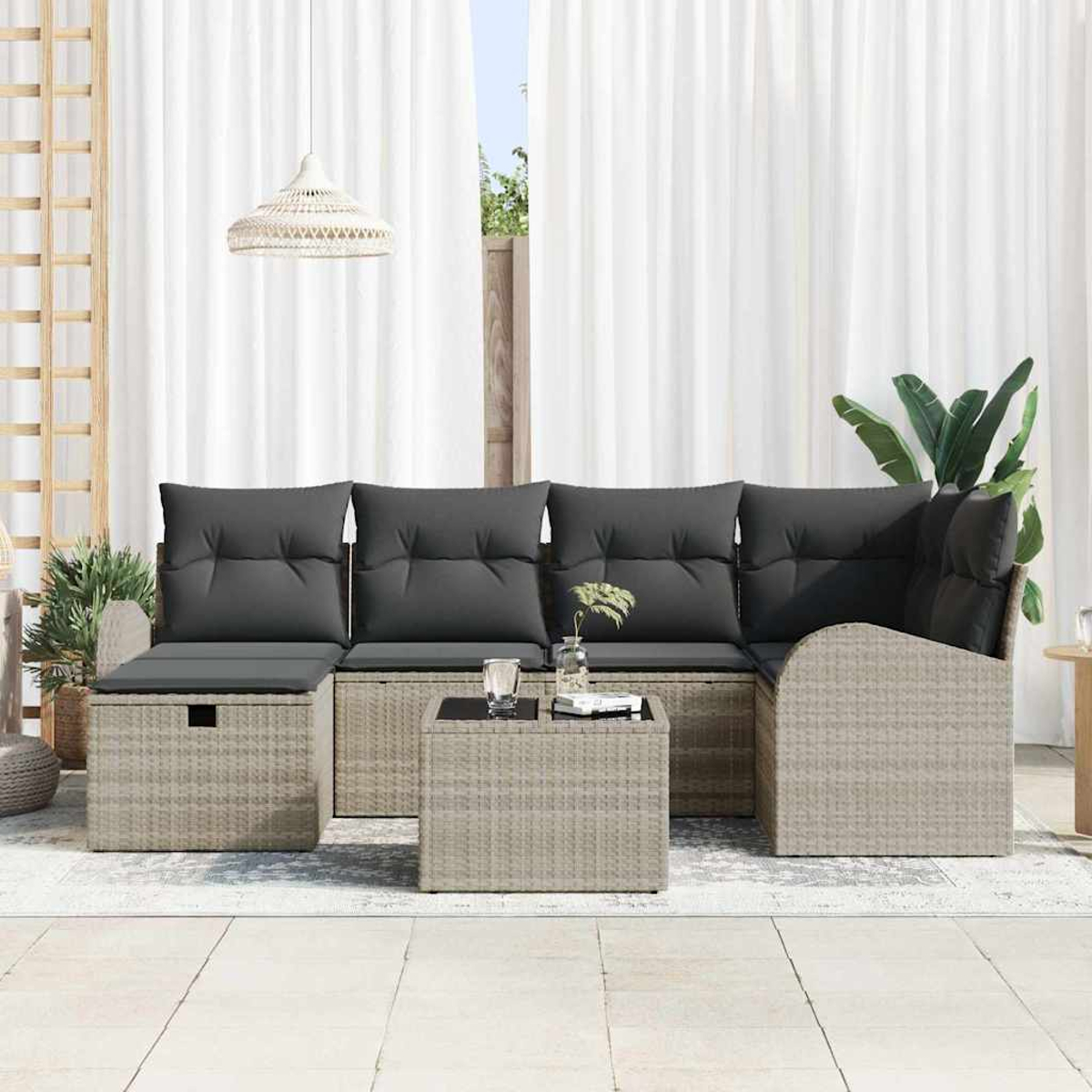 Outdoor-Korbsessel mit grauen Kissen, einem quadratischen Tisch und weißen Vorhängen im Hintergrund. Eine Lampe hängt oben.