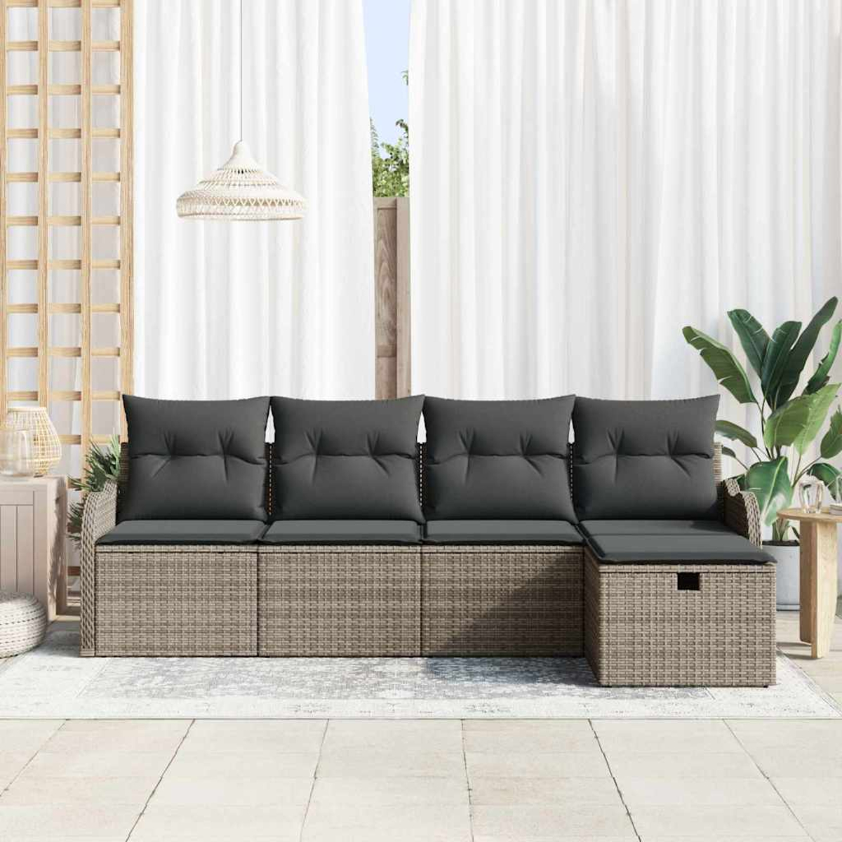 Ein Ecksofa aus Weide mit grauen Kissen. Weiße Vorhänge, eine Hängelampe und eine Pflanze befinden sich im Hintergrund.