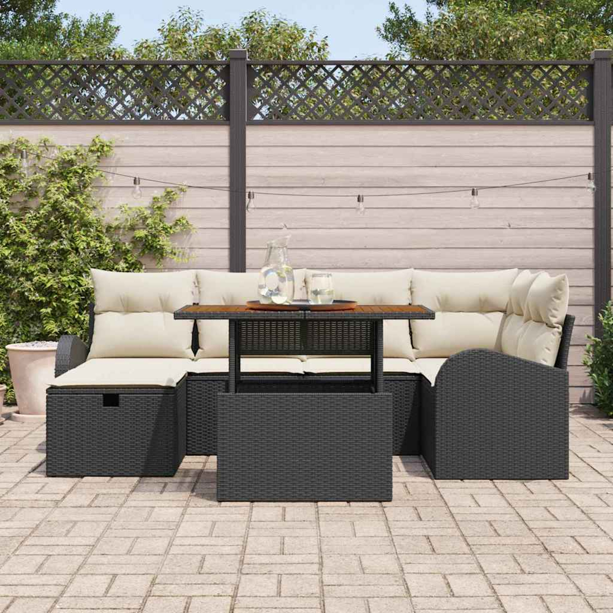 Gartenmöbel-Set mit Kissen, Couchtisch und Holzzaun. Ein Glas Wasser und eine Wasserflasche stehen auf dem Tisch.