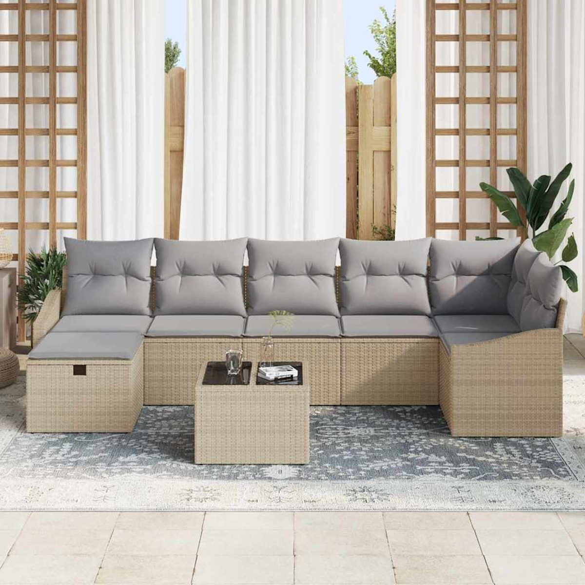 Gartenmöbel-Set mit grauen Kissen auf einem gewebten Untergestell, Tisch mit Glasplatte auf einem gemusterten Teppich.