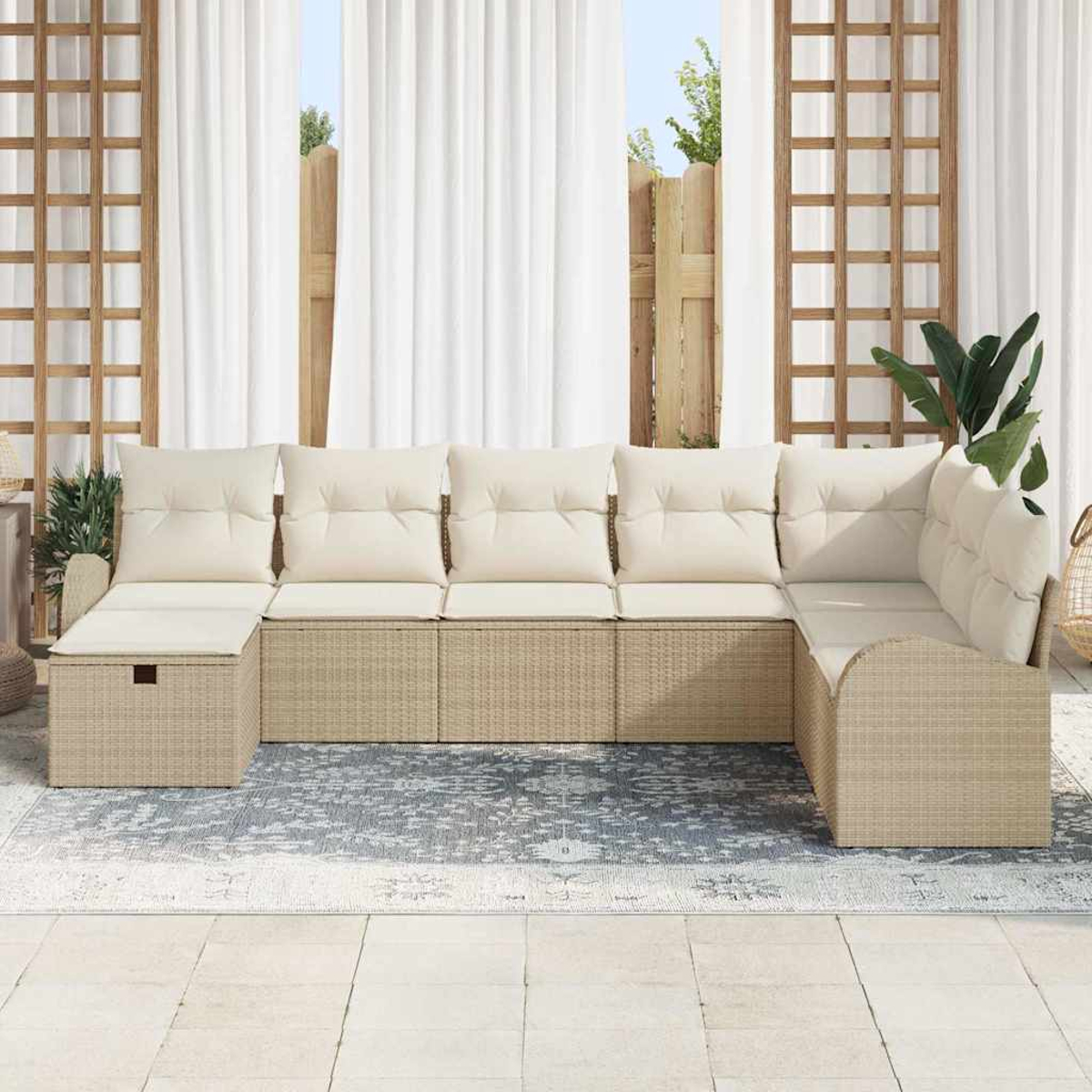 Ein beiges Korbsitzgruppensofa mit cremefarbenen Kissen steht im Freien auf einem gemusterten Teppich.