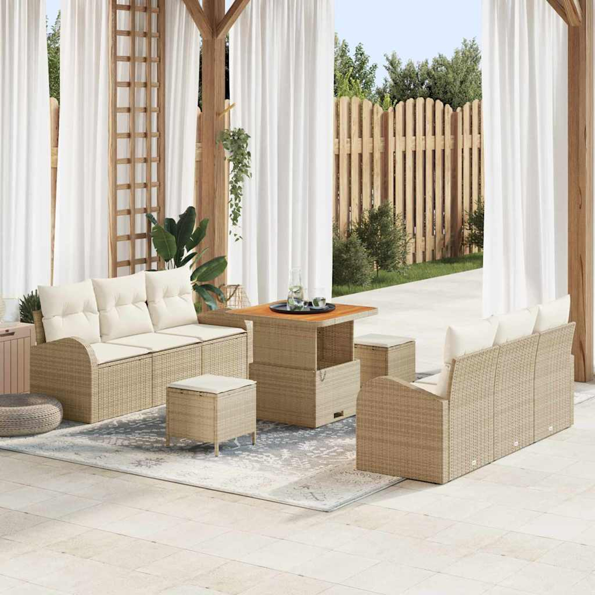 Terrassenset im Freien mit beigen Korbmöbeln, weißen Kissen und einem Holztisch. Weiße Vorhänge und ein Holzzaun im Hintergrund.