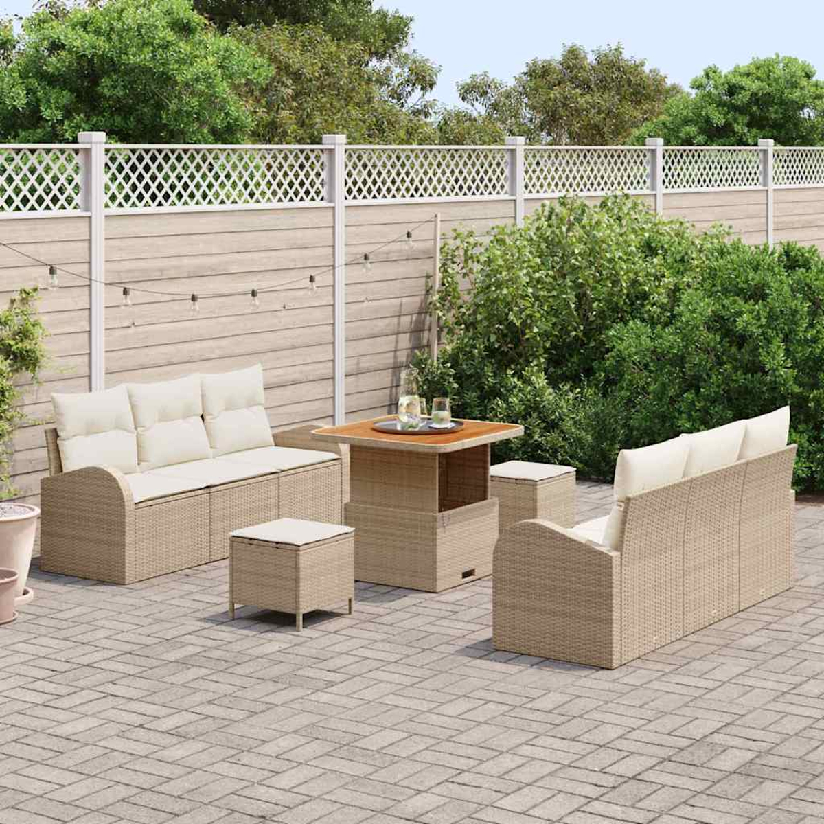 Garten-Terrassenset mit beigefarbenen Sofas, Tisch und Hockern aus Webstoff. Auf einer Backstein-Terrasse mit Holzzaun und grüner Kulisse.
