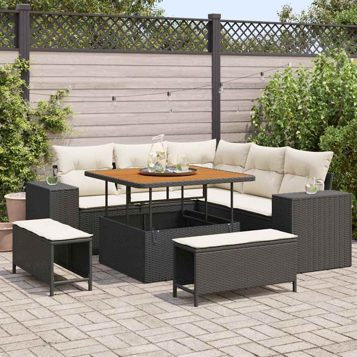 Set da patio esterno con tavolo, divano e sgabelli. I mobili sono in vimini grigio scuro con cuscini chiari.