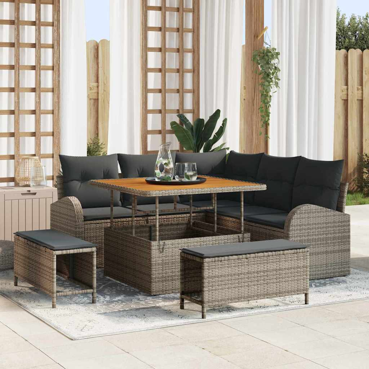 Terrassenset mit grauen Kissen, Holztisch und passenden Stauräumen. Weiße Vorhänge und ein Holzzaun sind im Hintergrund.