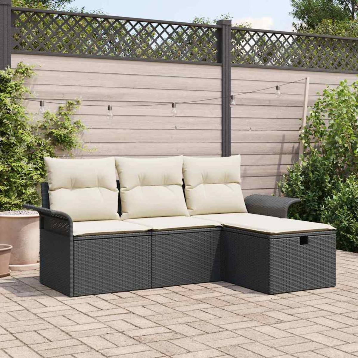 Ein dunkelgraues Korbsessel-Sofa mit cremefarbenen Kissen steht vor einem Zaun auf einer Ziegelterrasse.