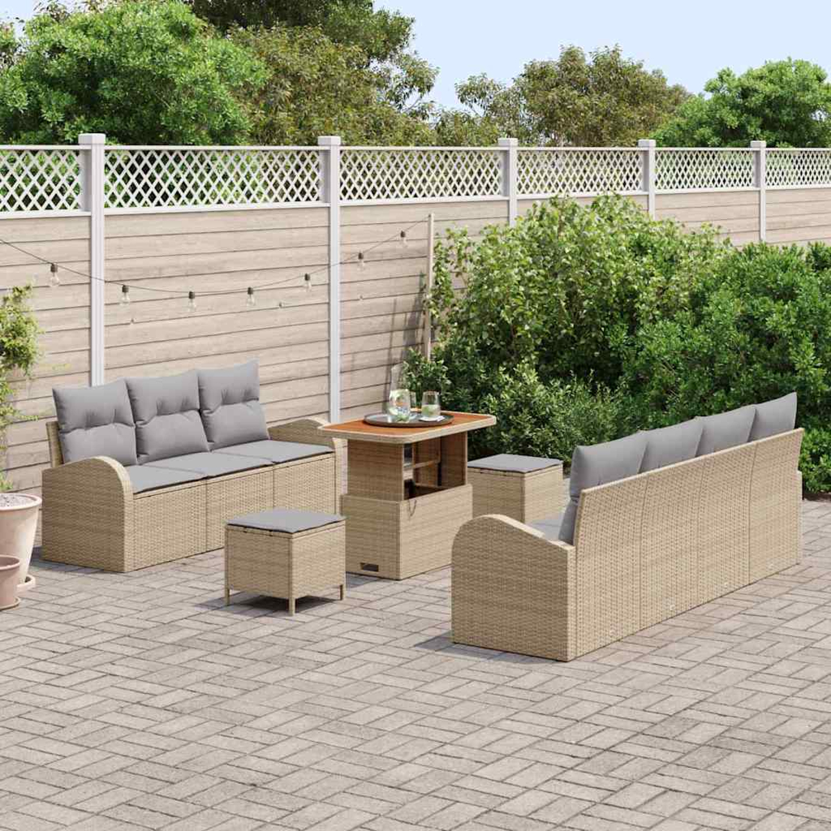 Gartenmöbel-Set. Beige Korbsessel mit grauen Kissen, Couchtisch und Ottomanen auf einer Backsteinterrasse, Zaun im Hintergrund.