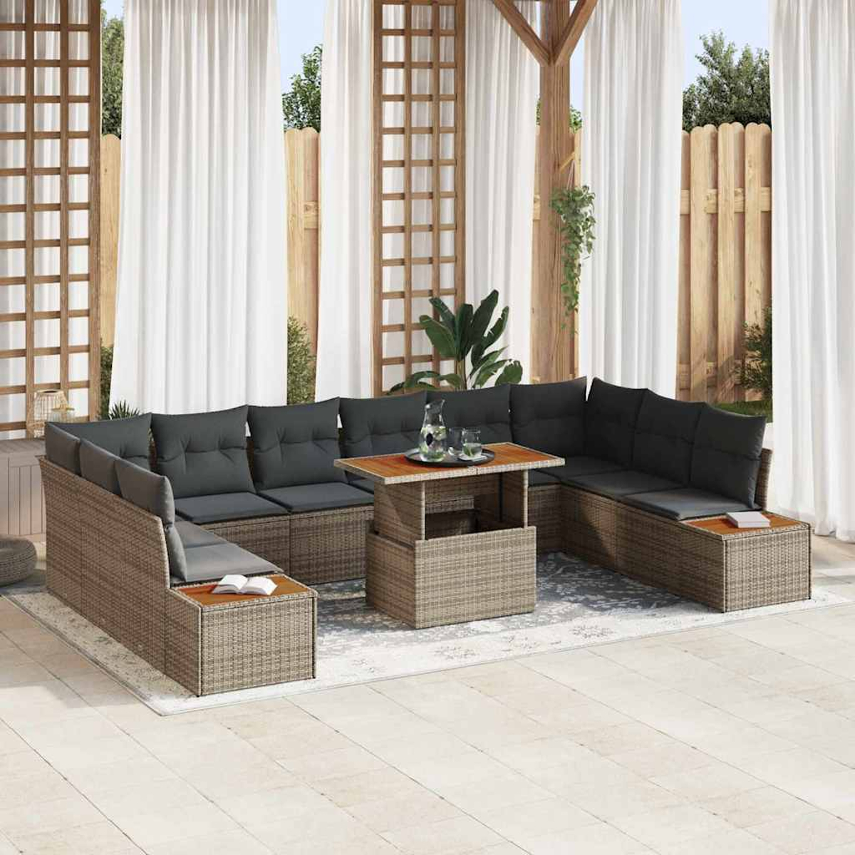 Sofá seccional exterior con cojines grises y mesa de madera. El fondo incluye cortinas blancas, enrejado de madera y valla.
