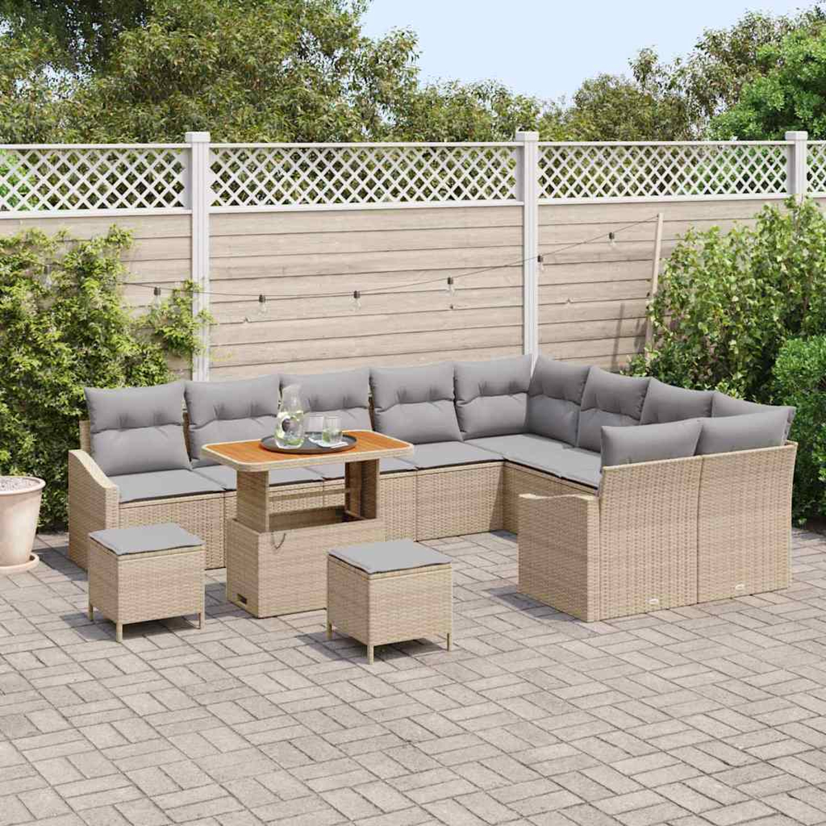 Ein Outdoor-Terrassenset mit grauen Kissen, einem Holztisch und zwei Hockern. Das Set steht auf einer gepflasterten Terrasse mit Zaun im Hintergrund.