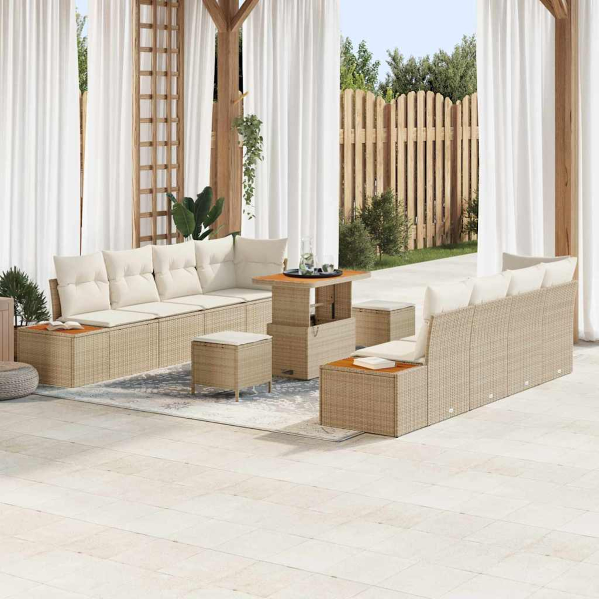 Gartenmöbel-Set. Enthält Sofas, Hocker und einen Tisch. Beiges Korbgeflecht mit weißen Kissen, auf einer Terrasse mit Vorhängen und einem Zaun.