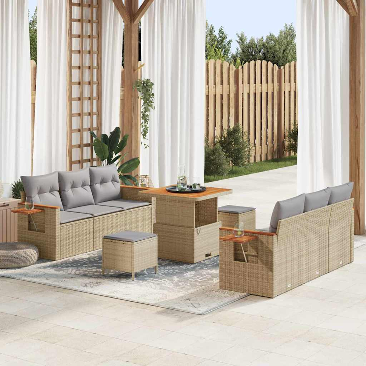 Outdoor-Rattan-Möbel-Set mit grauen Kissen. Enthält Sofas, Tisch und Ottomane, auf Terrasse mit Vorhängen und Holzzaun-Hintergrund.