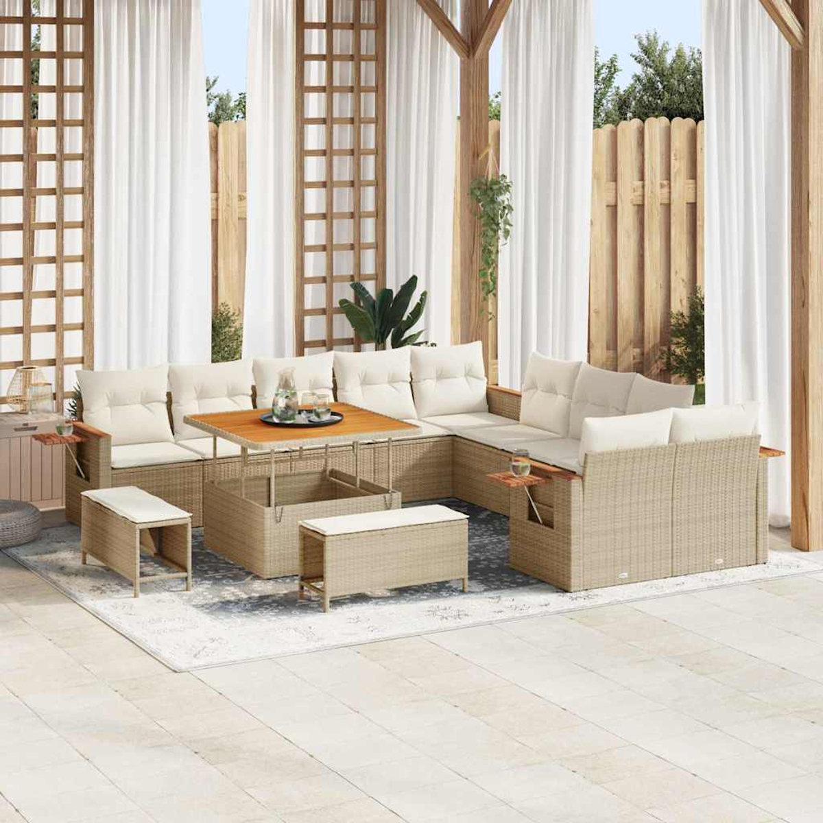 Set da patio all'aperto con divani beige, tavolo in legno e cuscini bianchi. Include tende, recinzione e verde.