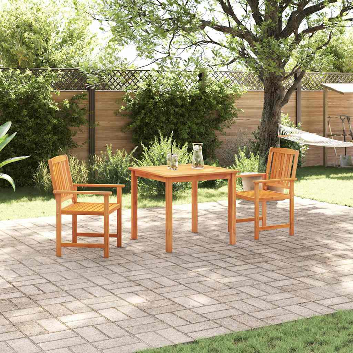 Szene im Freien: Holztisch und Stühle auf einer Ziegelterrasse. Grünes Gras und Laub umgeben den Terrassenbereich. Eine Hängematte hängt im Hintergrund.