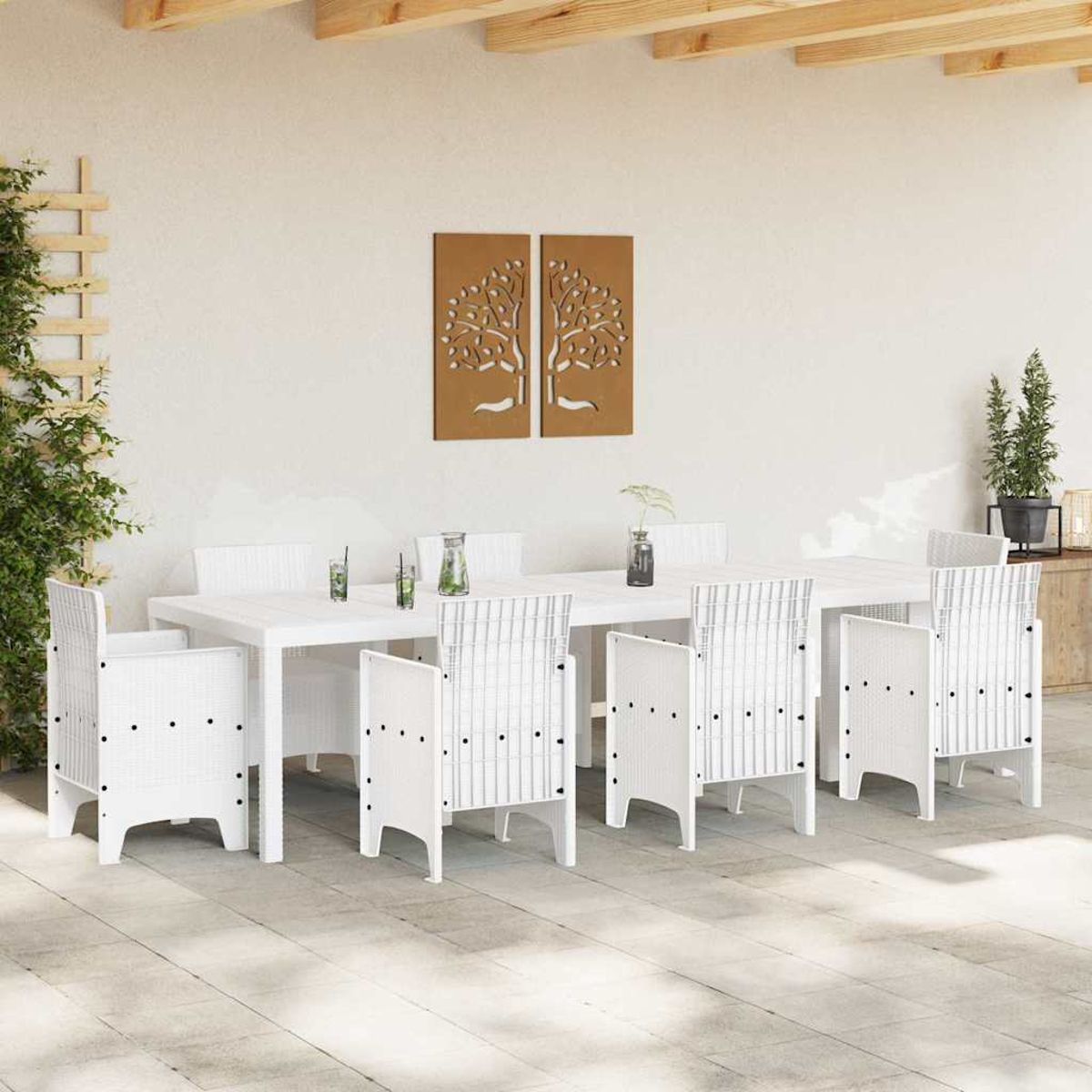 Conjunto de comedor al aire libre: mesa y sillas blancas. Arte de árbol marrón en la pared. Plantas verdes al lado. Suelo de baldosas.