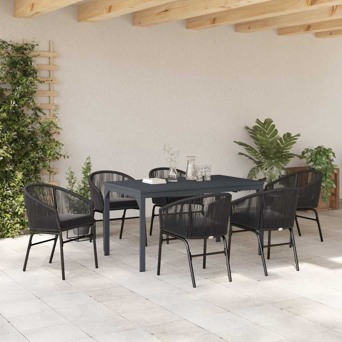 Essgruppe im Freien. Dunkelgrauer Tisch und Stühle. Pflanzen, Gläser und eine Kanne auf dem Tisch. Holzbalken darüber.