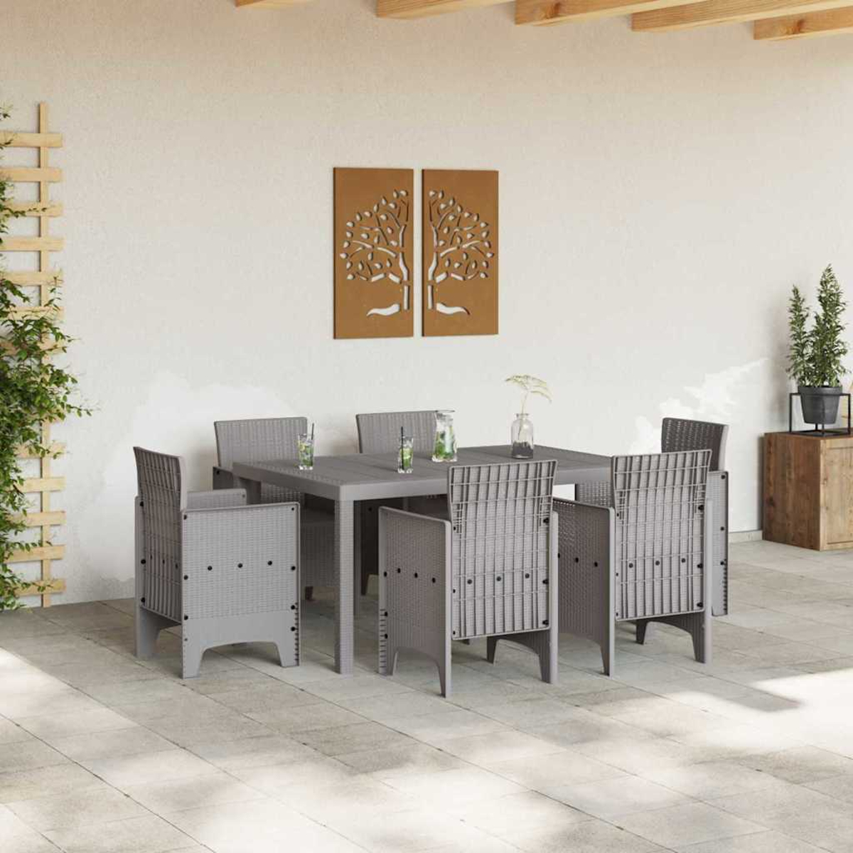 Szene im Freien: Grauer Tisch und Stühle, braune Baumkunst, Pflanzen, Getränke und eine Holzkiste. Weiße Wand und Terrasse.