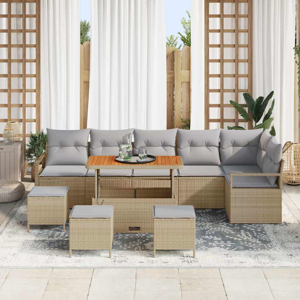 Outdoor-Sofa mit grauen Kissen, Holztisch und Hockern auf einem gemusterten Teppich. Weiße Vorhänge im Hintergrund.