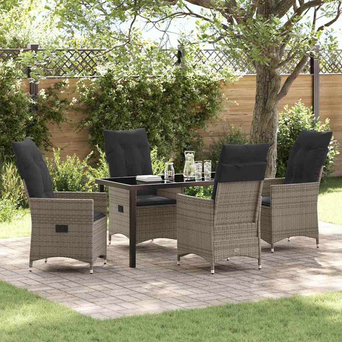 Essgruppe im Freien mit vier Stühlen um einen Tisch. Schwarze Kissen auf den Stühlen. Getränke auf dem Tisch. Terrasse mit Grün.