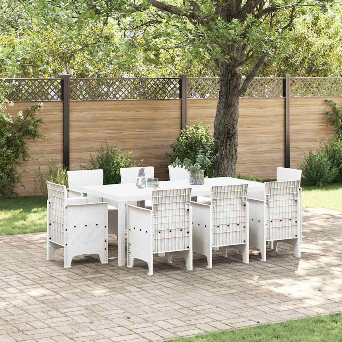 Weißes Ess-Set im Freien auf einer Terrasse, mit Tisch und Stühlen. Im Hintergrund ein Holzzaun und Bäume.