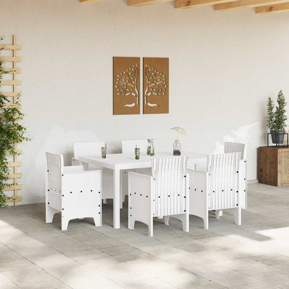 Weißes Ess-Set für draußen mit Tisch und Stühlen. Braune Baumkunst an der Wand. Pflanzen auf Holzkiste. Grauer Fliesenboden.