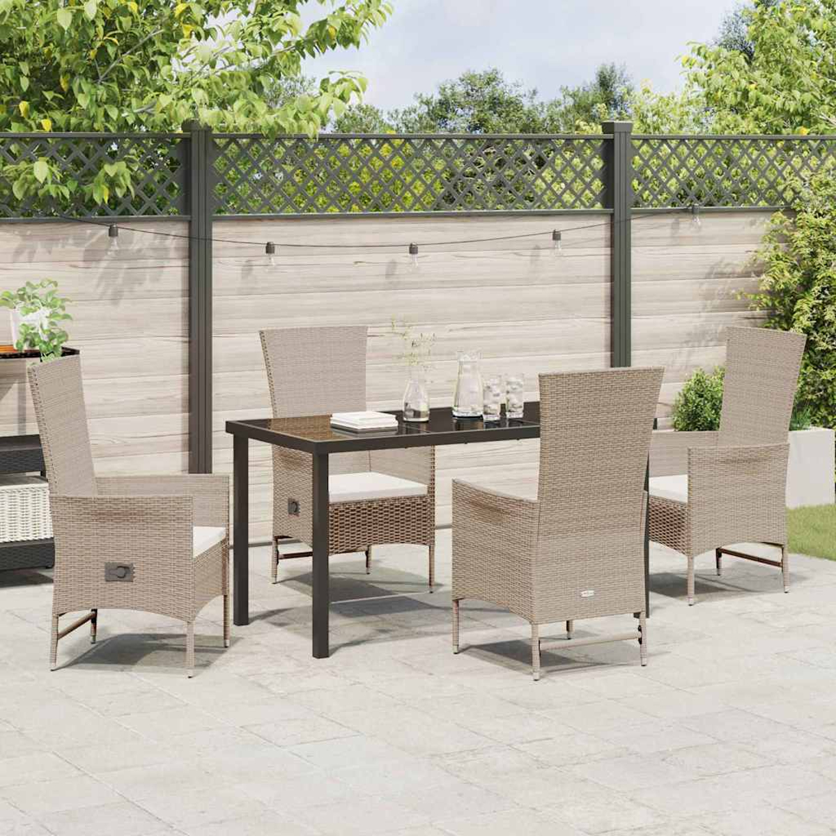 Terrasse mit Tisch, Stühlen und Zaun. Der Tisch ist mit Gläsern und einem Buch gedeckt. Stühle sind aus Korbgeflecht.