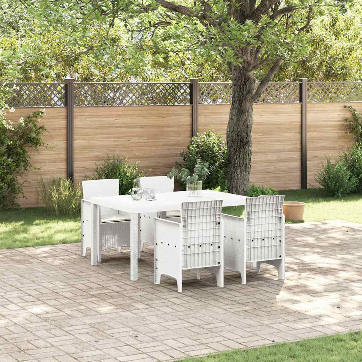 Weißes Outdoor-Tisch- und Stuhlset auf einer Terrasse. Ein Holzzaun und Bäume befinden sich im Hintergrund, mit grünem Gras.