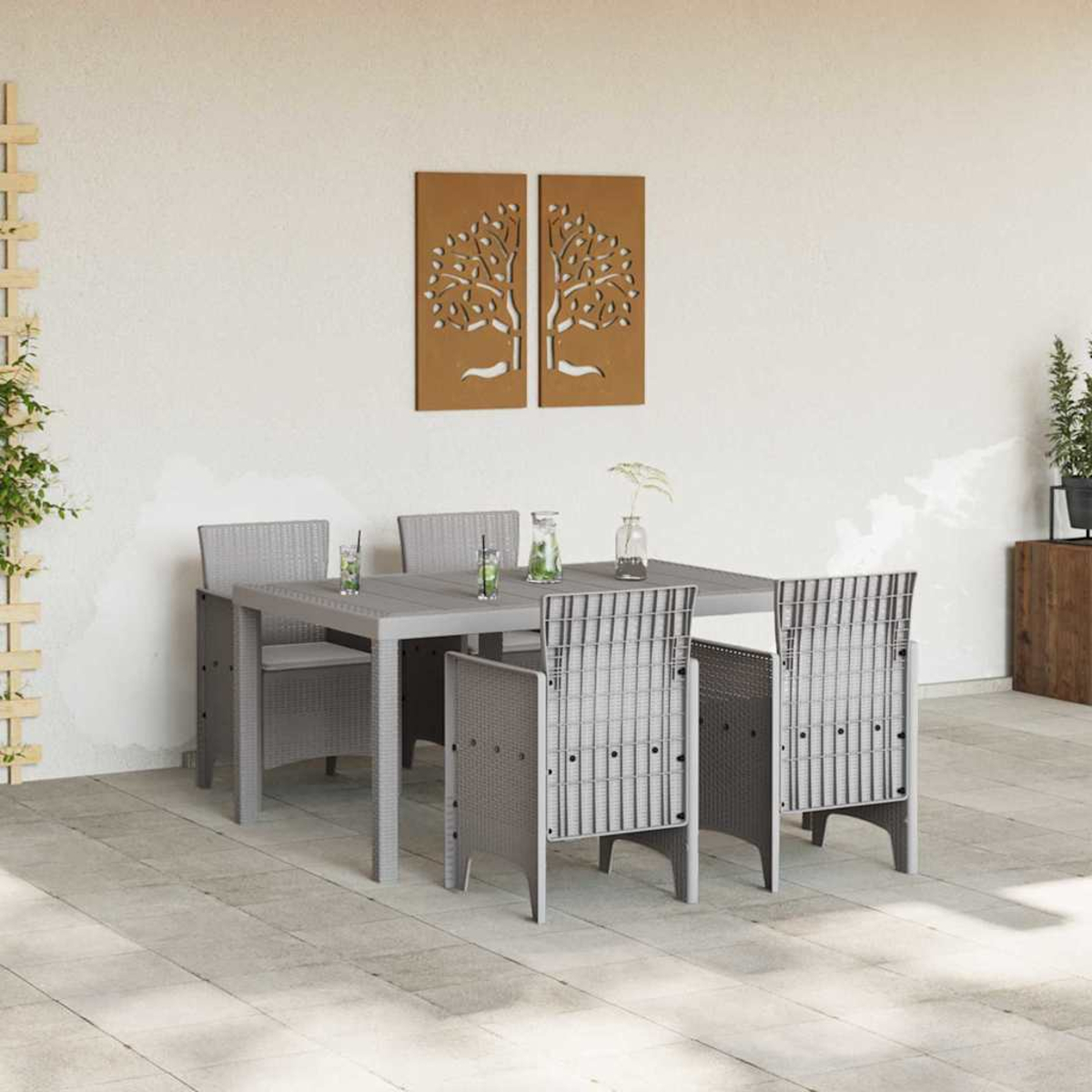 Set da pranzo all'aperto con tavolo, sedie e bevande grigie. L'arte dell'albero marrone è appesa al muro. Una pianta cresce su un supporto di legno.
