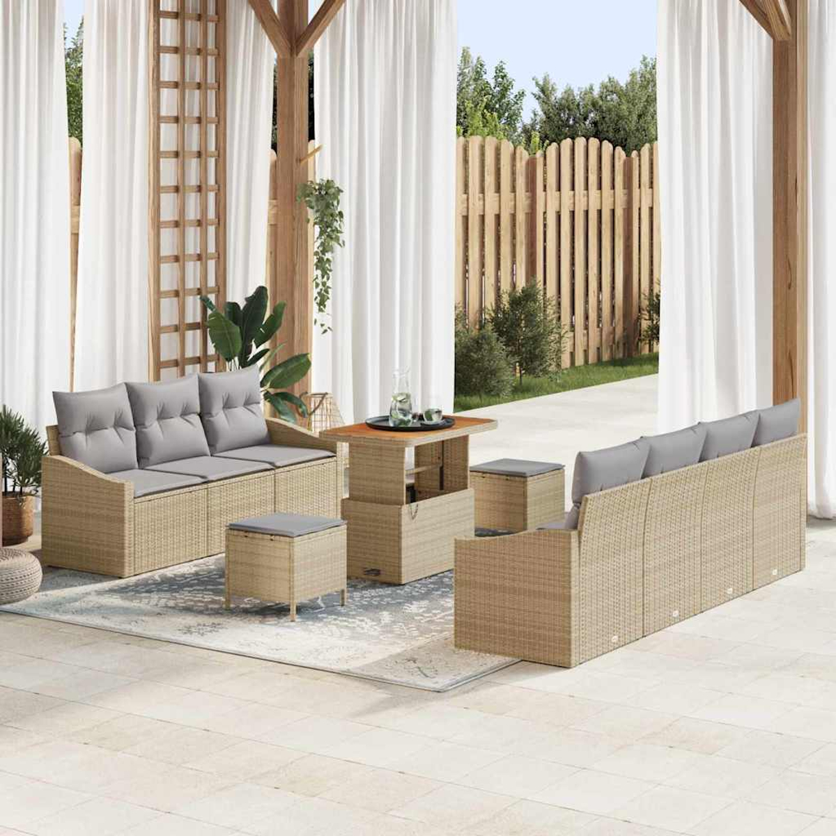 Terrassenset im Freien mit Sofas, Ottomanen und einem Tisch. Weiße Vorhänge, Holzzaun und Strukturen im Hintergrund. Neutrale Farben.