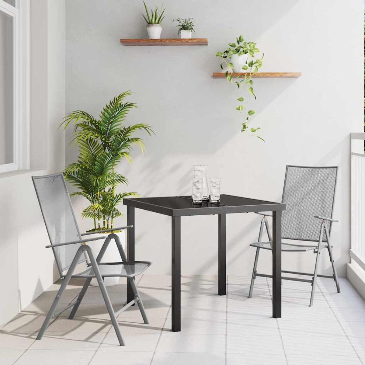 Balkonszene mit quadratischem Tisch, zwei Stühlen und Pflanzen. An der Wand befinden sich zwei Regale mit Pflanzen. Der Boden ist gefliest.