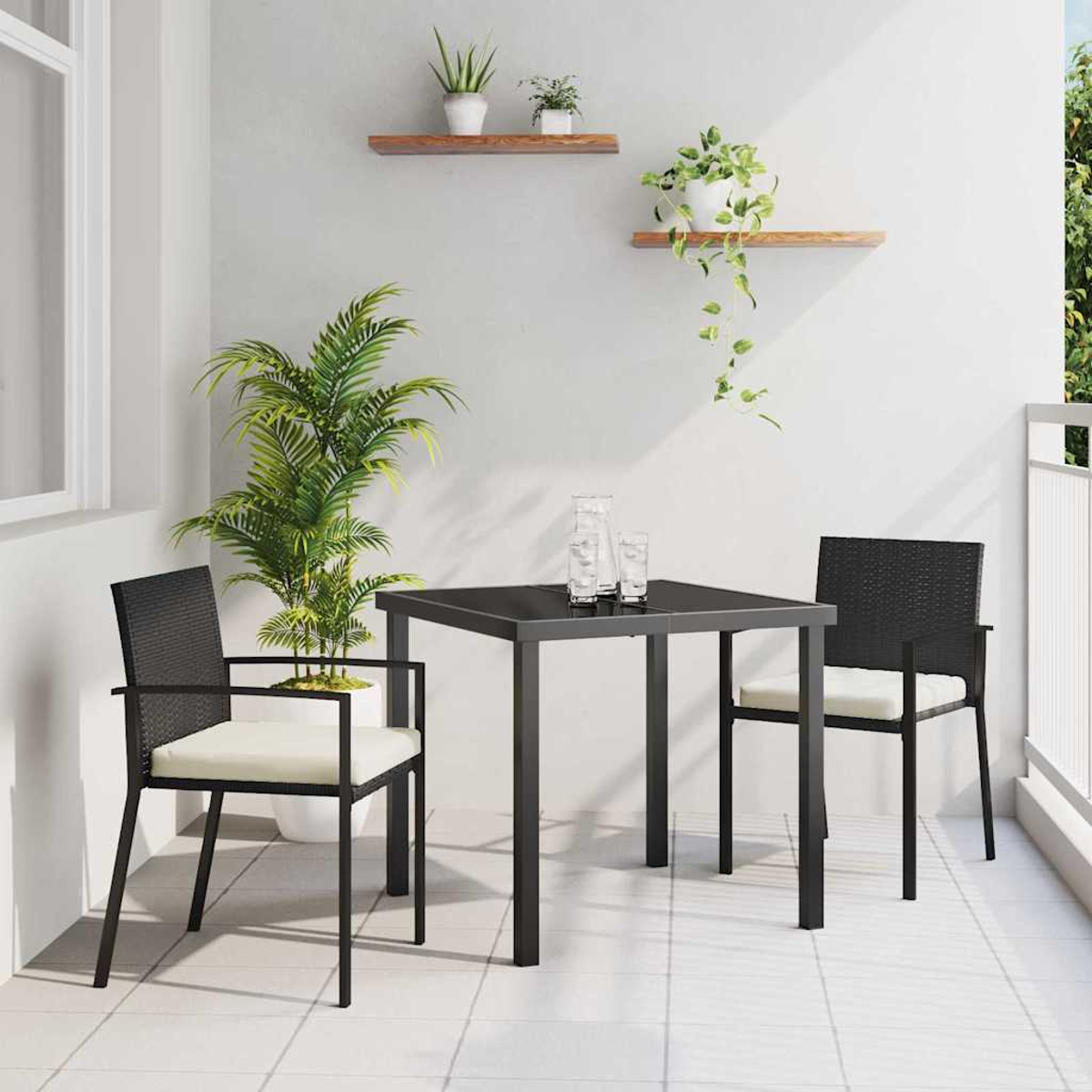 Ein Balkon mit einem schwarzen Tisch, Stühlen und Pflanzen. Zwei Stühle mit cremefarbenen Kissen stehen dem Tisch gegenüber. Pflanzen stehen auf Regalen und in Töpfen.