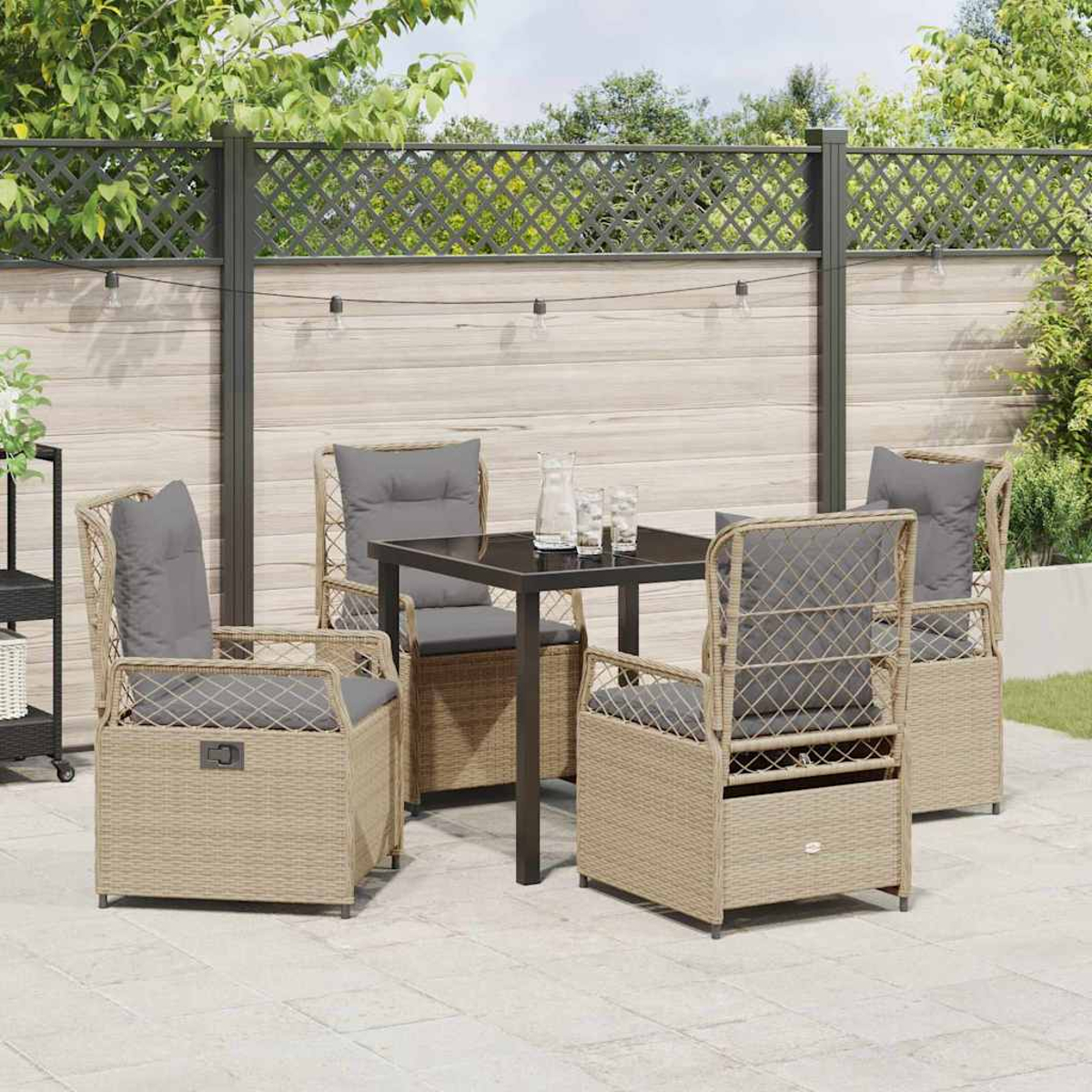 Terrassenset im Freien mit vier Korbstühlen und einem Tisch. Graue Kissen, dunkler Tisch und ein Zaun im Hintergrund.