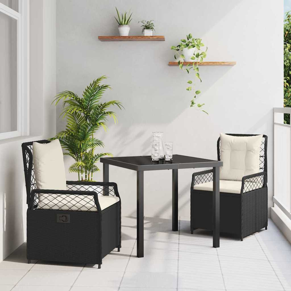 Ein kleines Outdoor-Terrassenset mit zwei schwarzen Stühlen, einem Tisch und Pflanzen. Kissen sind cremefarben. Weiße Wand und Boden.