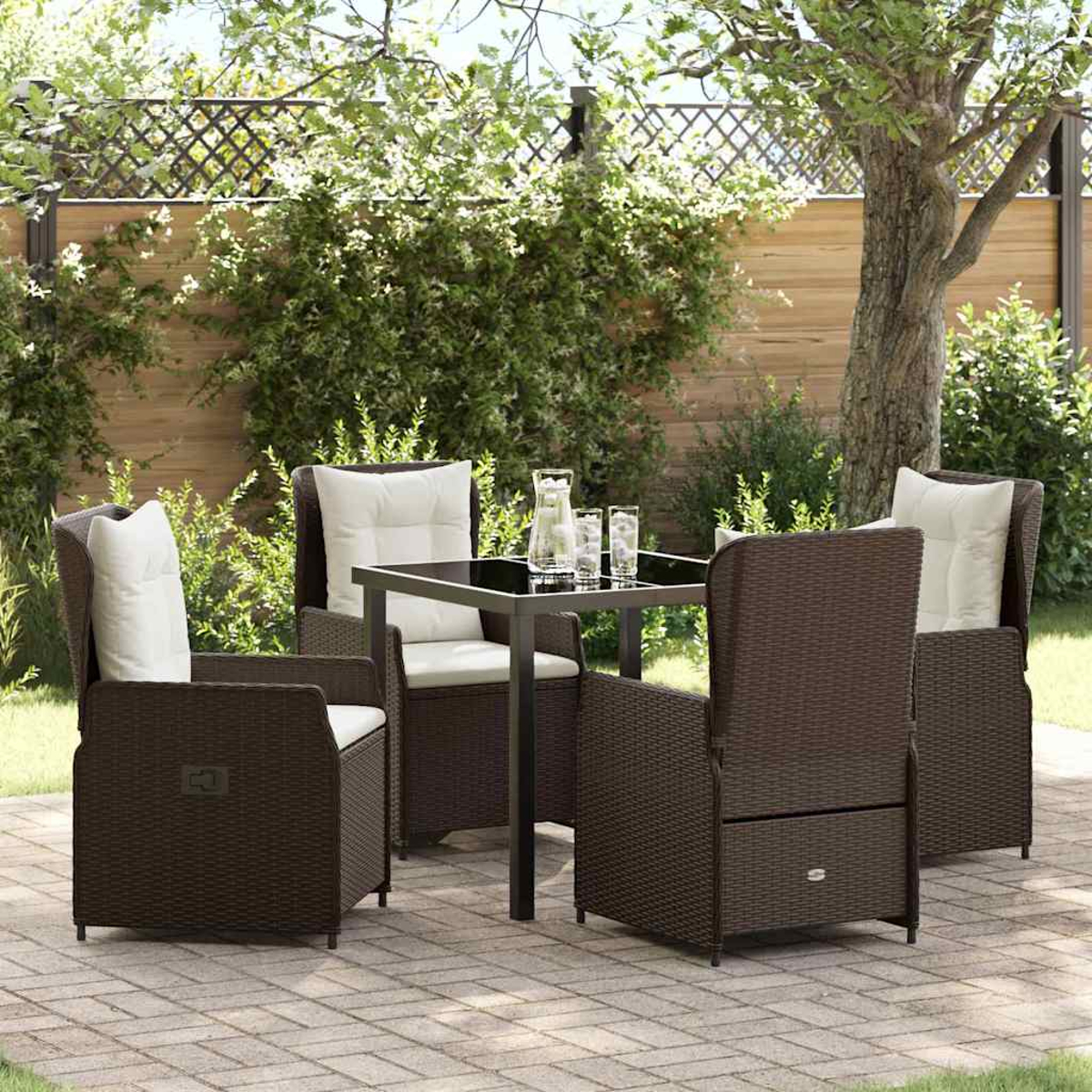 Garten-Terrassenset mit braunen Korbstühlen, weißen Kissen und einem quadratischen Tisch. Gläser, Wasserkrug und grünes Laub im Hintergrund.