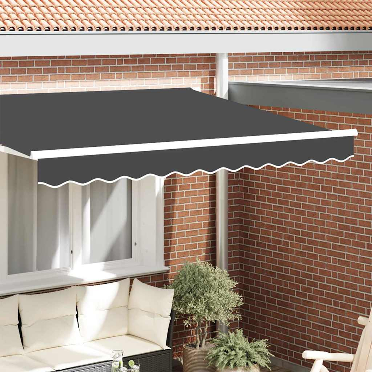 Un toldo gris sobre una ventana con marco blanco. Una pared de ladrillo al fondo y un sofá con cojines al frente.