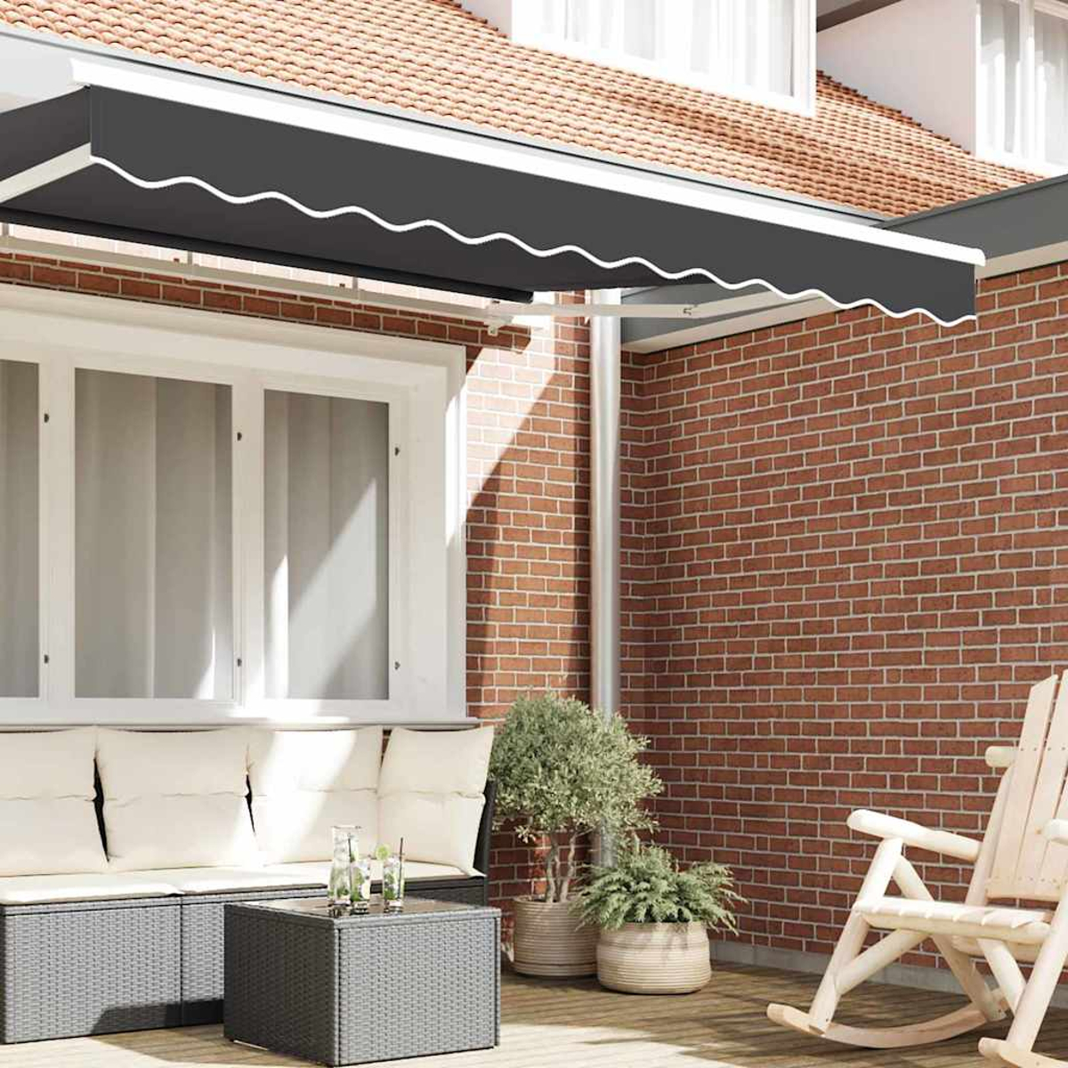 Un patio al aire libre con muebles grises, un toldo negro, plantas en macetas y una pared de ladrillo, iluminado por el sol.