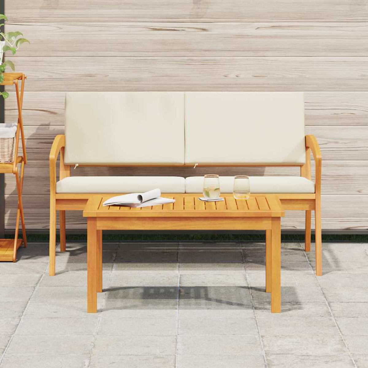 Set di sedute da esterno in legno con tavolino, due bicchieri e un libro. Lo sfondo mostra una parete in legno e un portavasi.