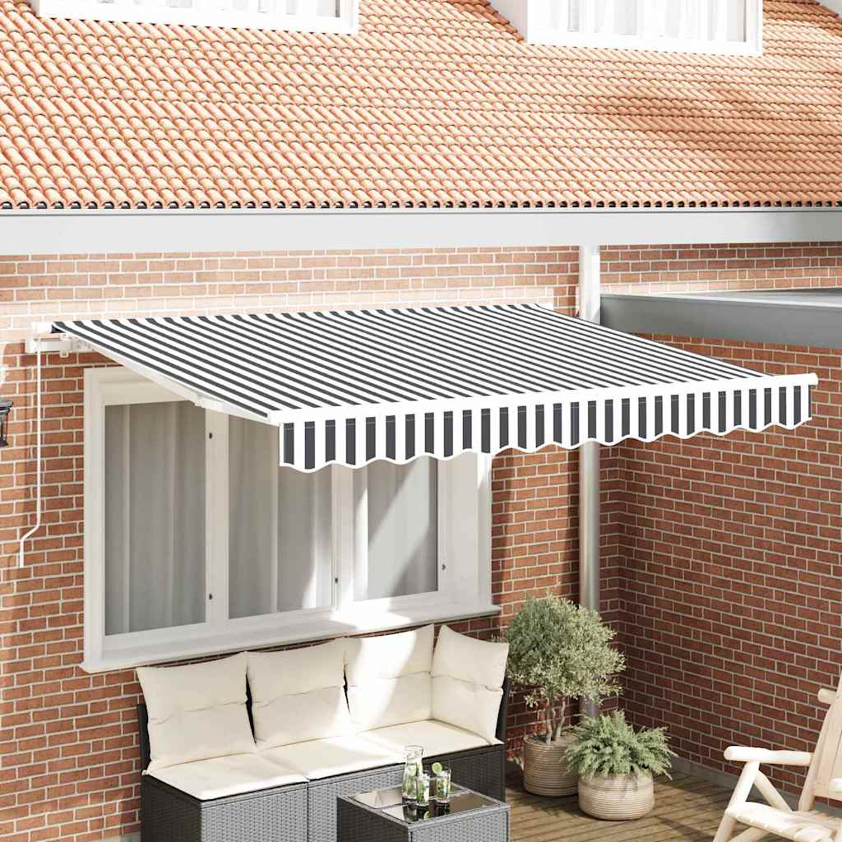 Ein Backsteinhaus mit einem schwarz-weiß gestreiften Vordach über einem Fenster. Auf der Terrasse gibt es ein Sofa und Pflanzen.