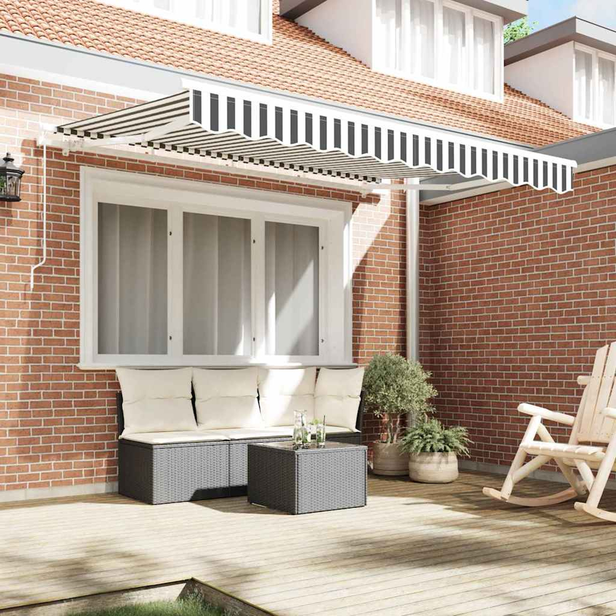 Eine Terrasse mit Backsteinmauer, gestreifter Markise, Sofa, Tisch, Pflanzen in Töpfen und Schaukelstuhl auf Holzterrasse.