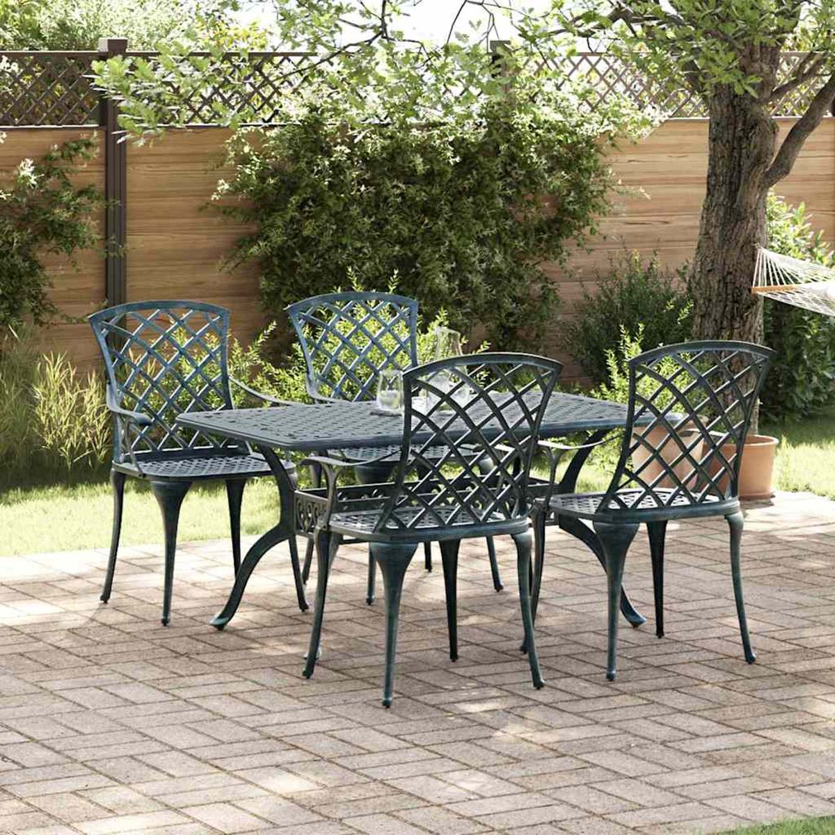 Gartenmöbel mit Tisch und vier Stühlen. Grüne Stühle und Tisch stehen auf einer Ziegelterrasse, im Hintergrund ein Holzzaun.