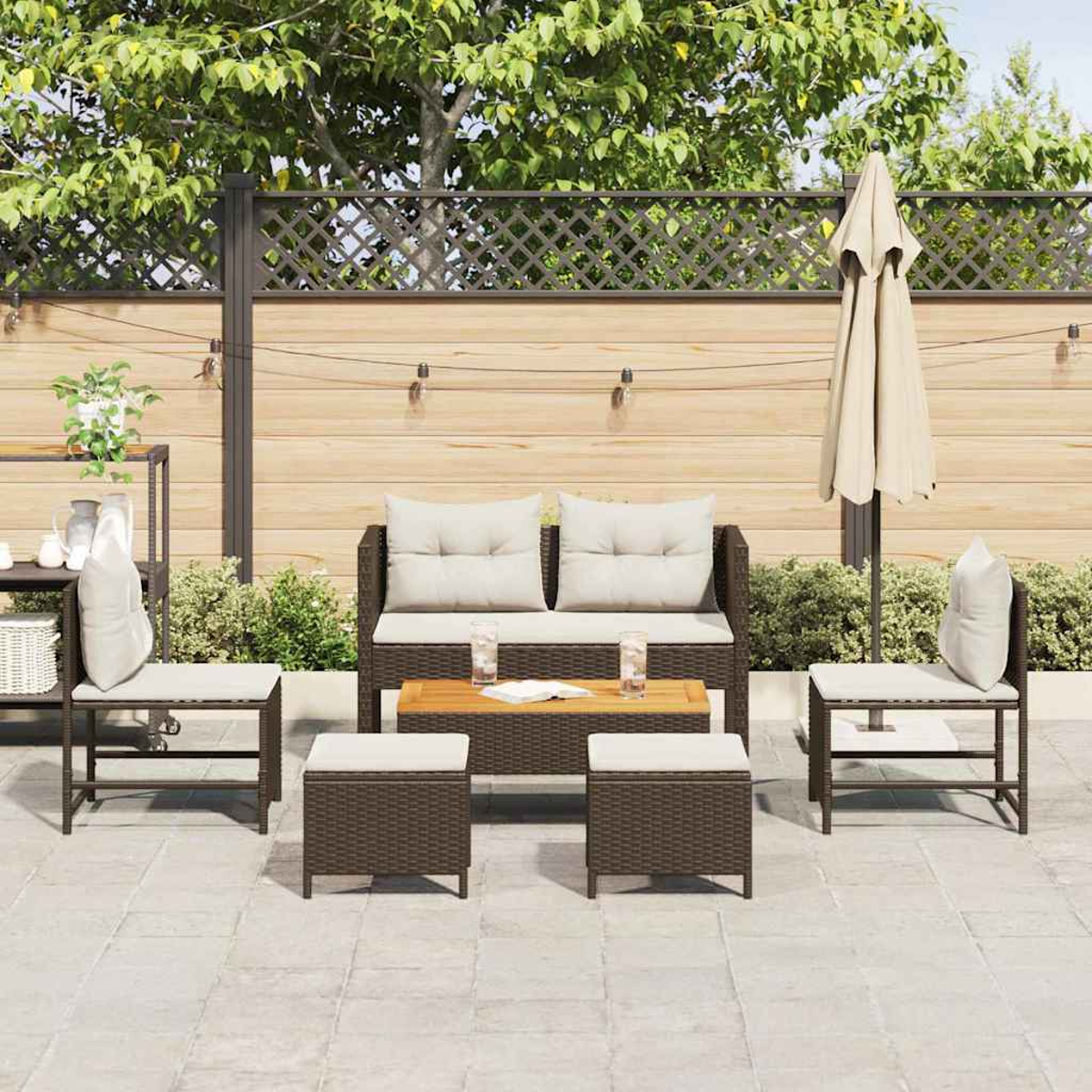 Terrassenset mit Sofa, Stühlen und Hockern. Beige Kissen, braune Webmöbel, Holztisch und ein geschlossener Schirm.