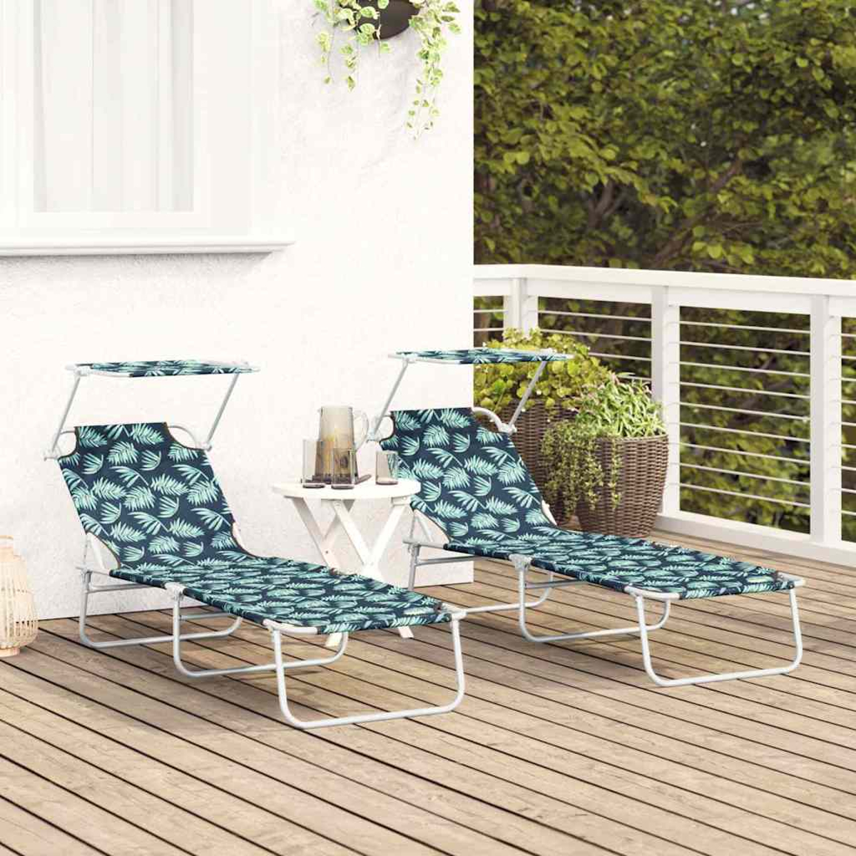 Zwei blaue Liegestühle mit Blattmuster und Sonnenschutz sitzen auf einem Holzdeck. Zwischen ihnen steht ein kleiner Tisch mit einem Krug. Grün im Hintergrund.