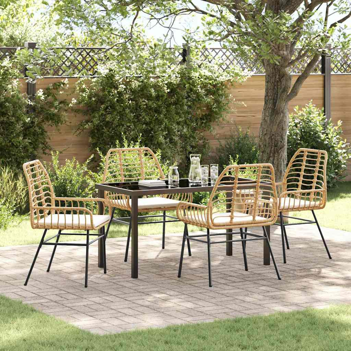 Essgruppe im Freien: Korbstühle, schwarzer Tisch, Wassergläser auf einer Terrasse. Grünes Gras und ein Baum im Hintergrund.