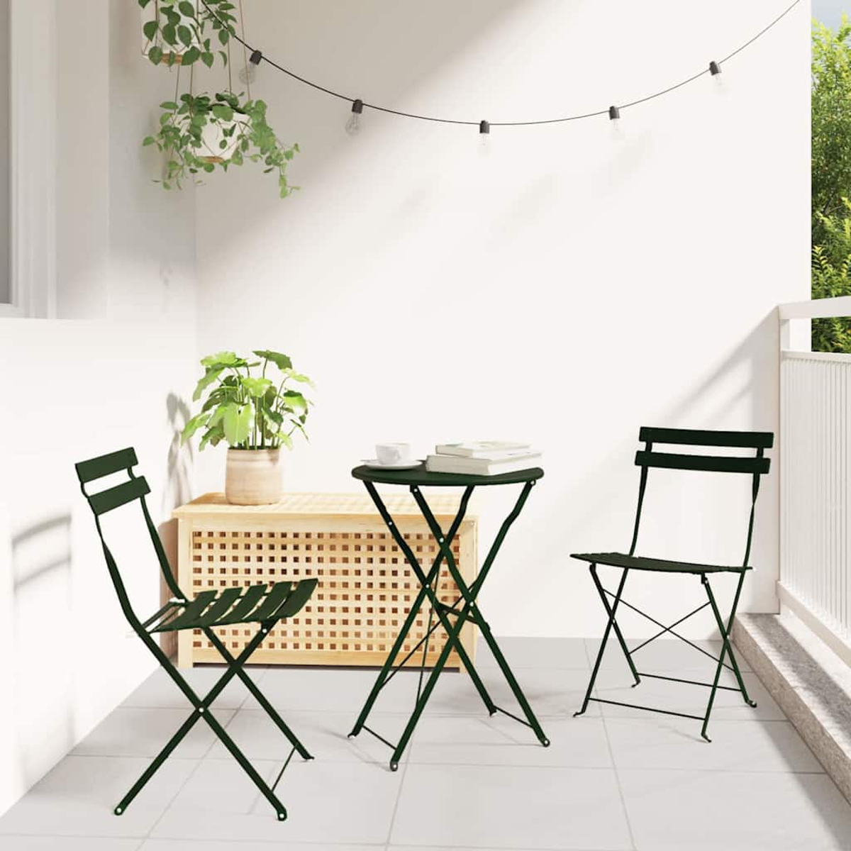 Ein Outdoor-Set mit Tisch und zwei Stühlen. Eine Topfpflanze steht auf einem Holzschrank. Lichterketten hängen darüber.