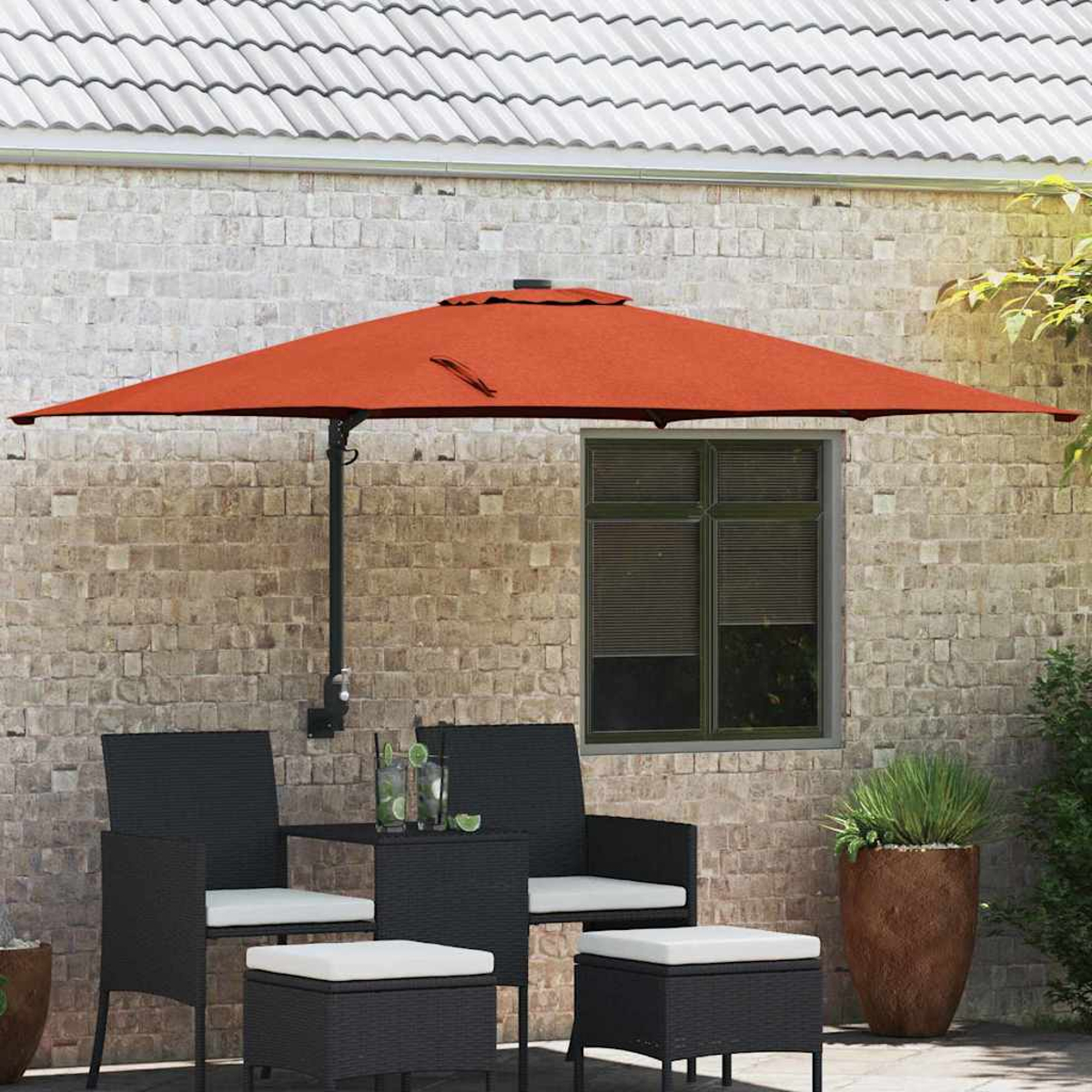 Ein orangefarbener Sonnenschirm beschattet einen Tisch und Stühle. Backsteinmauer im Hintergrund. Ein Fenster und ein Blumentopf sind ebenfalls vorhanden.