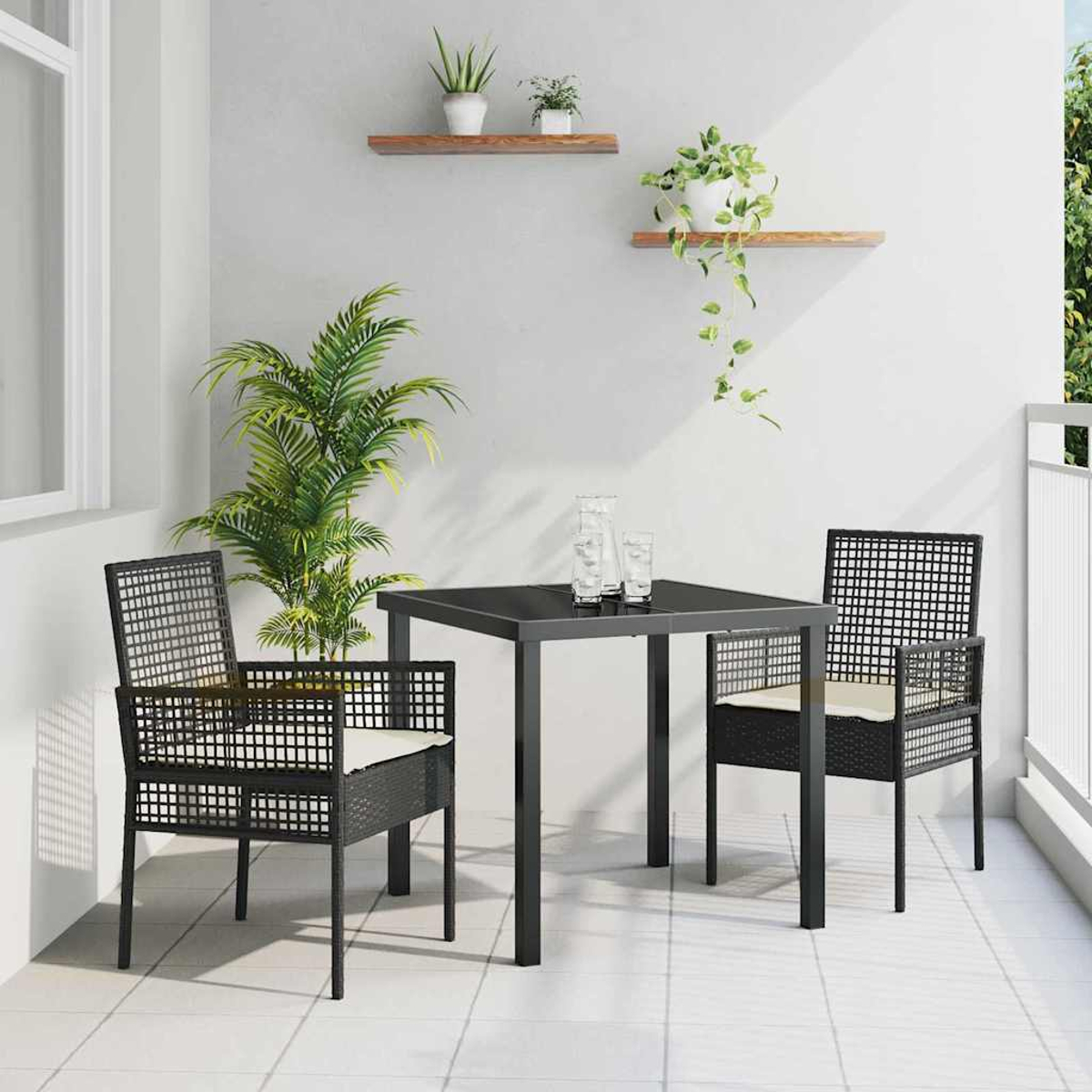 Balkonszene mit schwarzem quadratischem Tisch, Stühlen und Pflanzen. Zwei Stühle mit cremefarbenen Kissen stehen dem Tisch gegenüber. Pflanzen schmücken die Wände.