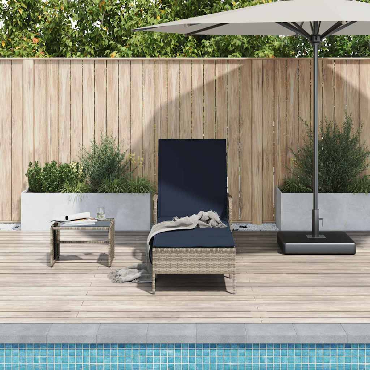 Eine Szene am Pool mit Liegestuhl, kleinem Tisch und Sonnenschirm. Im Hintergrund ein Holzzaun und grüne Pflanzen.