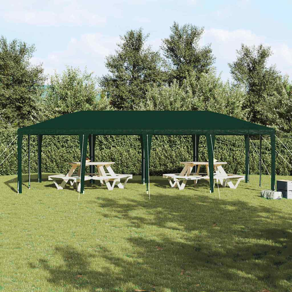 Una tenda verde copre tavoli da picnic sull'erba. Gli alberi sono sullo sfondo. La scena è ambientata all'aperto.